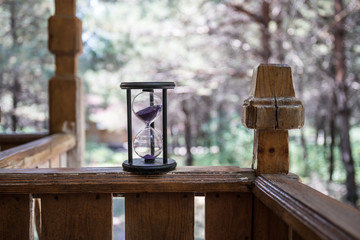 Sand running through the bulbs of an hourglass measuring the passing time in a countdown to a deadline, on a colorful background with copy space. Abstract old sand-glass in forest.