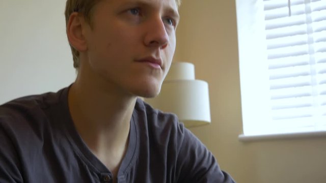 Focused young man playing a video game using a wireless controller.