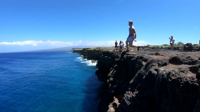 Slow Motion shot of a man doing a gainer off of a cliff at South Point, Big Island, Hawaii.