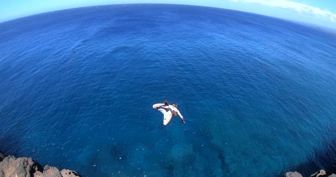 Slow Motion shot of a man doing a gainer off of a cliff at South Point, Big Island, Hawaii.