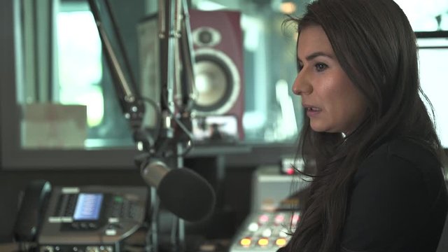 young female radio host speaking into the microphone gesticulating with hands