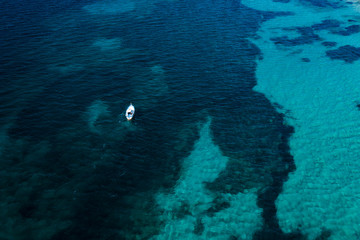 View from above, stunning aerial view of a beautiful fishing boat with a fisherman on board sailing on a blue sea. Amalfi coast, Italy