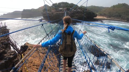 PoV action camera - person go on suspension bridge above ocean waves in Timang beach, Java island, Indonesia
