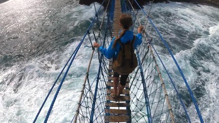PoV action camera - person go on suspension bridge above ocean waves in Timang beach, Java island, Indonesia
