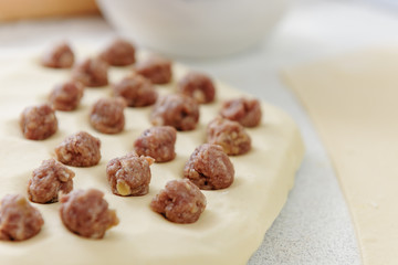 Prepare homemade dumplings on the table, sprinkled with flour. Dumplings with minced meat sculpts cook in the kitchen. Homemade meat dumplings. Sculpt dumplings.