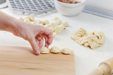 Sculpt dumplings. Homemade meat dumplings.Dumplings with minced meat sculpts cook in the kitchen. Prepare homemade dumplings on the table, sprinkled with flour.