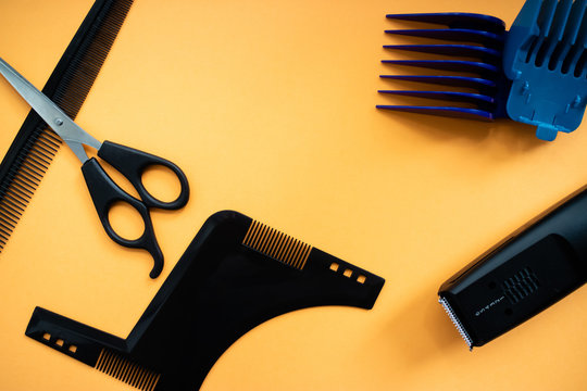 Barber set with scissors, comb, electric razor and heards on yellow background.  Flat lay