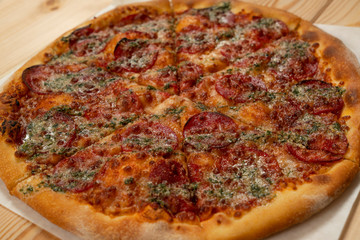 Salami pizza with basil sauce on wooden background - Close up