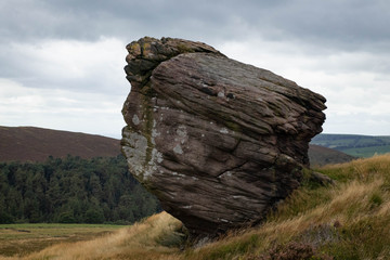 A big boulder standing in the Peak District with a moody sky behind it
