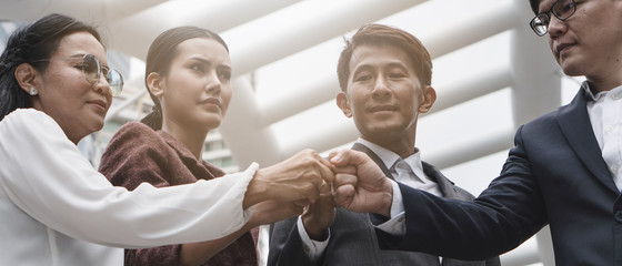 group of asian business people having hands in fists together