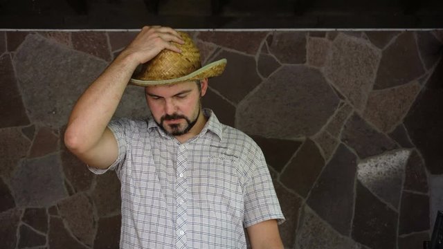 A man with a straw hat is sad. Mourns for the departed. On the face is a beard. Portrait to the waist. 4K video