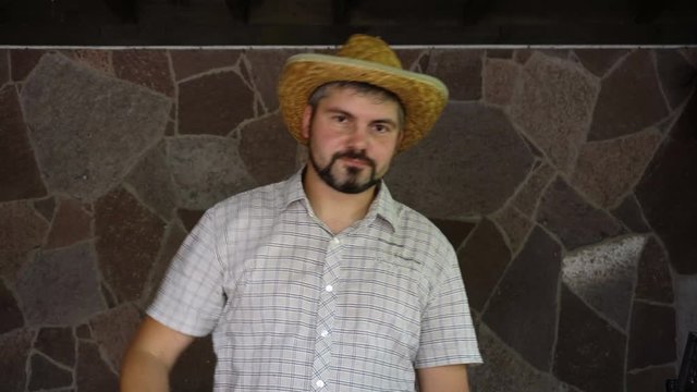 The man mourns. It is sad. In the hand is a straw hat. On the face is a beard. Starts to dance and rejoice. Portrait to the waist. 4K video