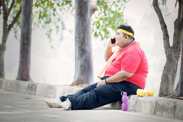 Fat man talking on a phone after exercise