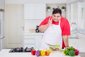 Obese man thinking an idea in the kitchen