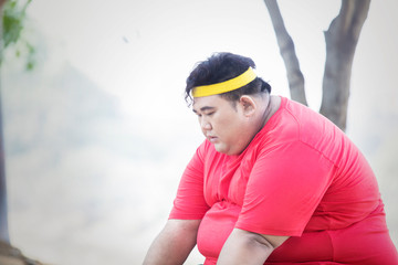 Overweight man looks tired in the park