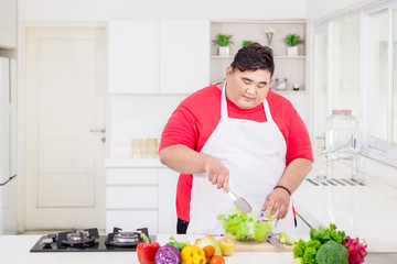 Overweight man making a bowl of healthy salad