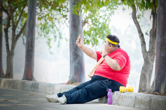 Overweight man taking selfie after exercises in park
