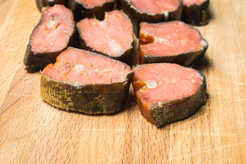 Smoked fish pink salmon sliced on wooden cutting board.