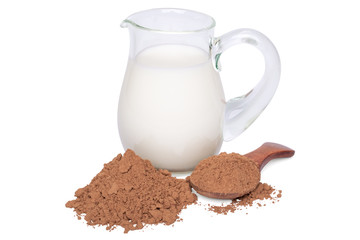 Milk in a glass jug and a heap of cocoa powder