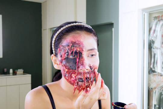 Young woman putting bloods makeup on her face