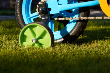 Fototapeta premium closeup little green support wheel and metal gear chain of the small child bicycle