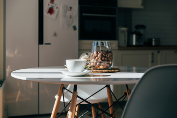 Macadamia nuts in a bowl and cup of tea or coffee stand in the kitchen table, hard morning light
