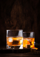 Old Fashioned - classic alcoholic cocktail with bourbon whiskey, bitter, cane sugar and ice in retro glasses on vintage bar counter, place for text