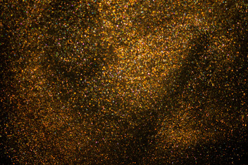 Golden glitter dust on dark background.