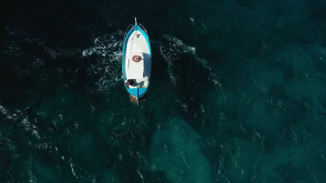 View from above, stunning aerial view of a beautiful fishing boat with a fisherman on board, sailing on a blue sea. Amalfi coast, Italy
