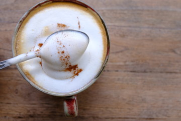 cup of coffee with cream on wooden background