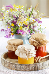 Jars with honey and bouquet of wild flowers in the garden.