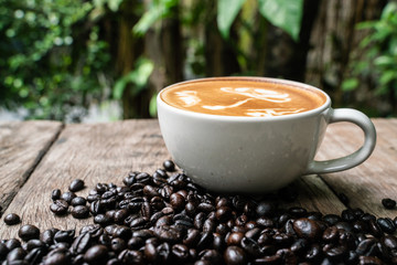 Latte art coffee cup with coffee bean on wood table