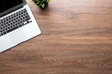 Wood office desk table with laptop computer and grass pot. Top view with copy space, flat lay.