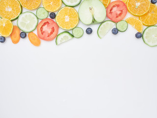 Fresh fruits and vegetables sliced on white background