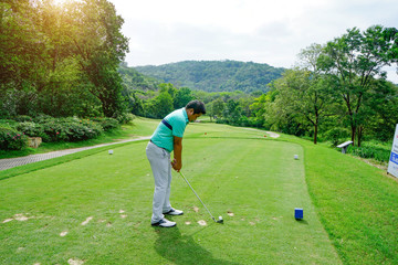 Blurred golfer playing golf in beautiful golf course in the evening golf course with sunshine in thailand