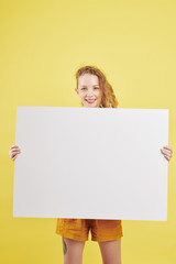 Portrait of positive lovely female college student holding white paper placard