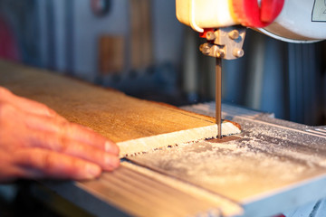 Carpenter Cutting a Piece Of Wood With Bandsaw In Workshop