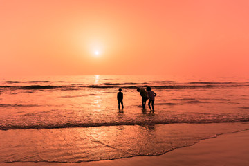 Sillhoute of a family on the beach watching sunrise in the morning during vacation