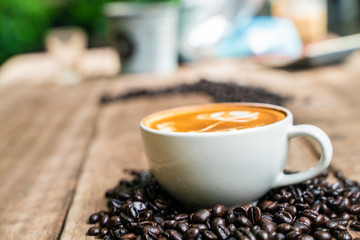 Latte art coffee in white cup with roast bean