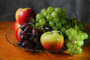 autumn still life red apples and ripe grapes of different varieties on a dish