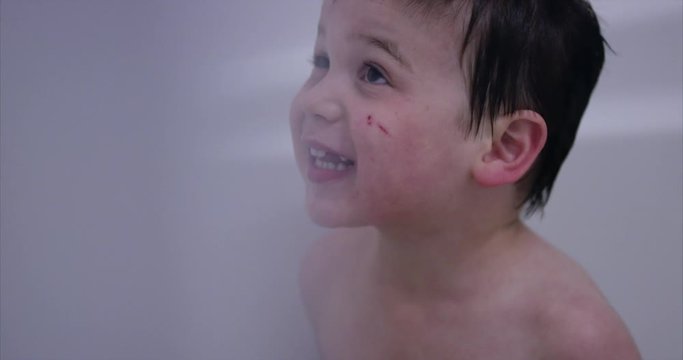 Toddler boy singing to himself in bathtub - close up on face