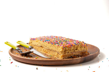 Peruvian food: Turron "Doña Pepa". Traditional dessert of Peru. Wooden plate and cutlery. White background.