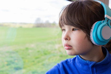 the girl looks out the window of the train and listening to music in headphones.