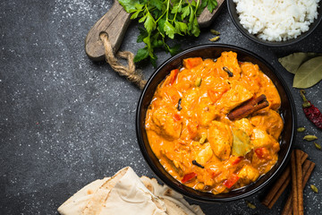 Chicken tikka masala with rice on black top view.