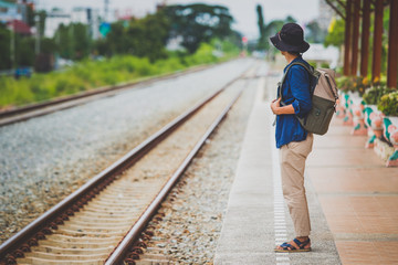 man with backpack walking away on railroad and emphasize to patience and survey trying step forward to goal. copy space