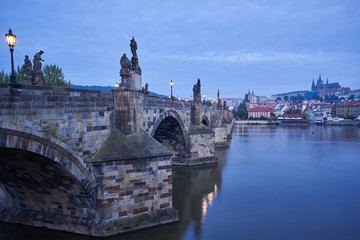 Landscape Picture of romantic Charles bridge with Prague castle on other bank of Vltava river in Prague taken in blue hour before sunrise, famous european gothic style architecture in Czech republic.