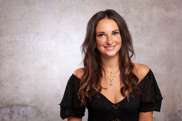Fototapeta premium Junge Frau Braune Haare Business mit Whitespace vor Betonwand