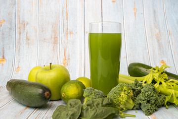 Freshly blended green smoothie in a glass on wooden background. Template for detox recipe, copy space. Vegetarian, healthy food.
