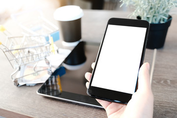 Woman is showing digital cell phone  blank screen on work desk in coffee shop.