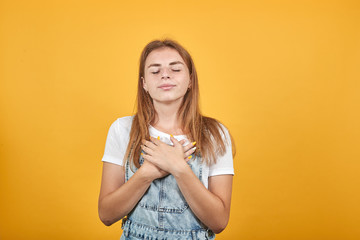 Young woman wearing white t-shirt, over orange background shows emotions